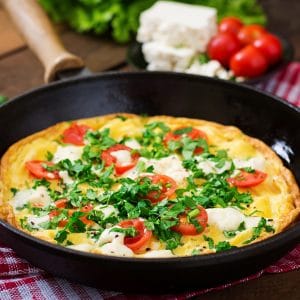 Omelet with tomatoes, parsley and feta cheese in pan