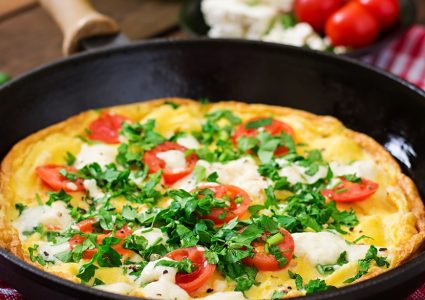 Omelet with tomatoes, parsley and feta cheese in pan